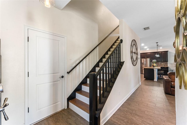 stairway with recessed lighting, visible vents, baseboards, and wood finished floors