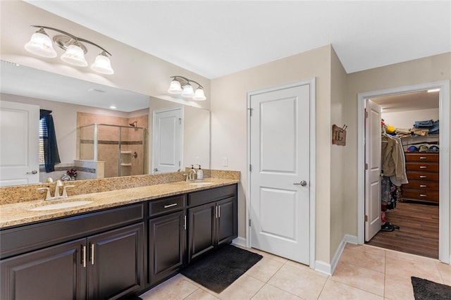 bathroom featuring tile patterned floors, double vanity, a stall shower, and a sink