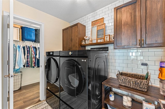 laundry room with baseboards, washing machine and dryer, wood finished floors, cabinet space, and a textured ceiling