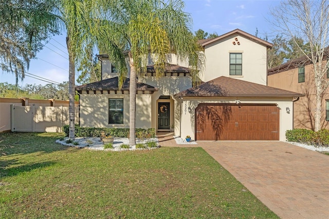 view of front facade with a front lawn, decorative driveway, fence, and stucco siding