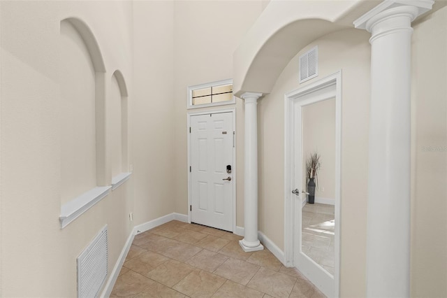 foyer entrance with light tile patterned flooring, visible vents, baseboards, and decorative columns