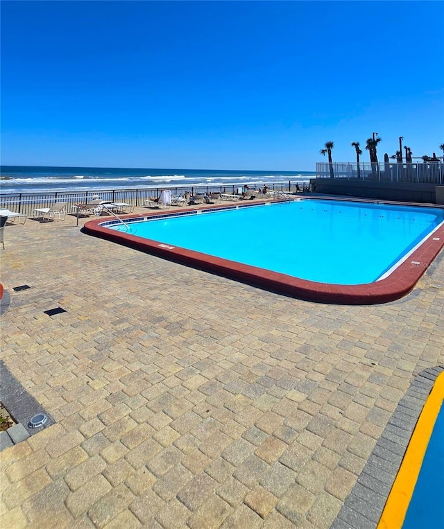 pool featuring a patio area and a water view