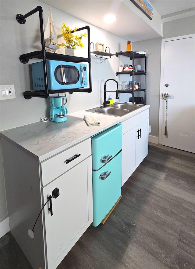 kitchen with a sink, dark wood-type flooring, light countertops, white cabinets, and open shelves