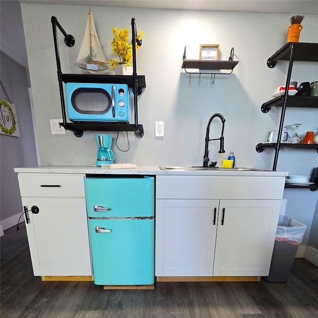 bar featuring a sink, baseboards, dark wood finished floors, and freestanding refrigerator