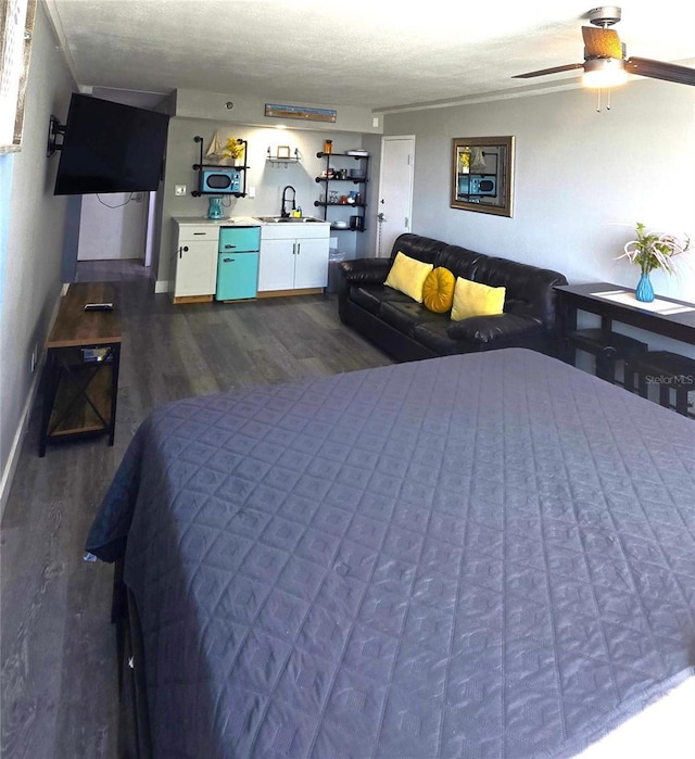 bedroom featuring dark wood-style floors, baseboards, ceiling fan, a sink, and a textured ceiling