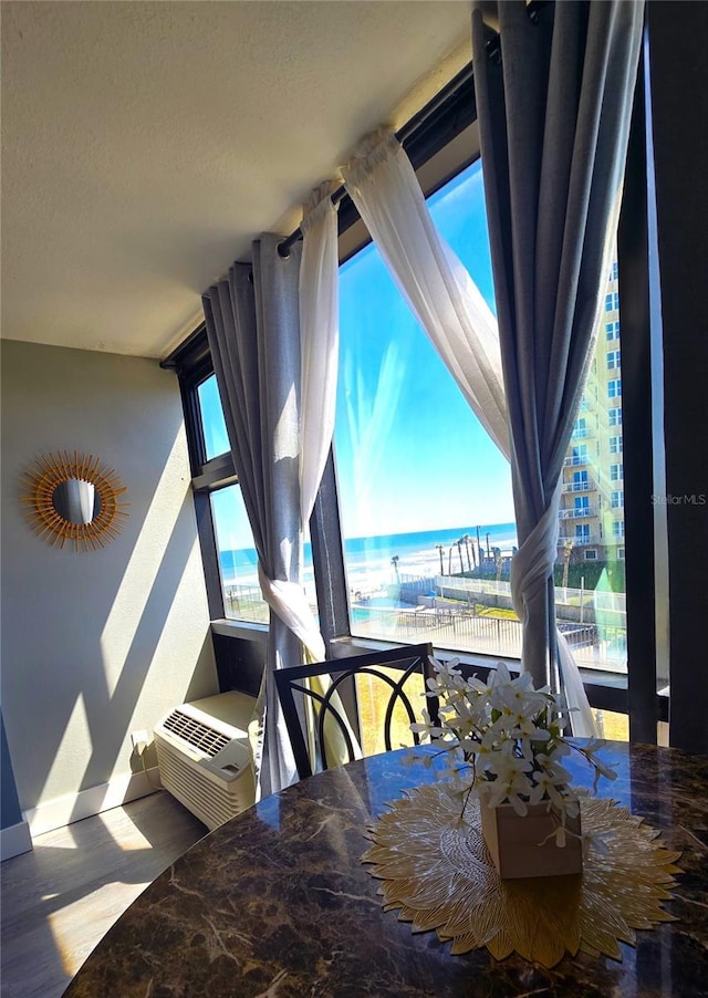 unfurnished dining area with a wall mounted air conditioner, plenty of natural light, wood finished floors, and a water view