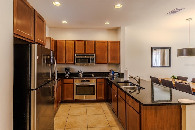 kitchen with visible vents, dark stone countertops, appliances with stainless steel finishes, a peninsula, and a sink