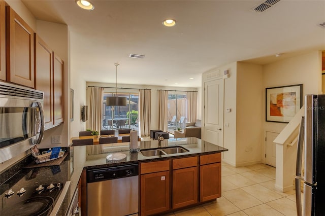 kitchen featuring visible vents, a peninsula, brown cabinetry, stainless steel appliances, and a sink