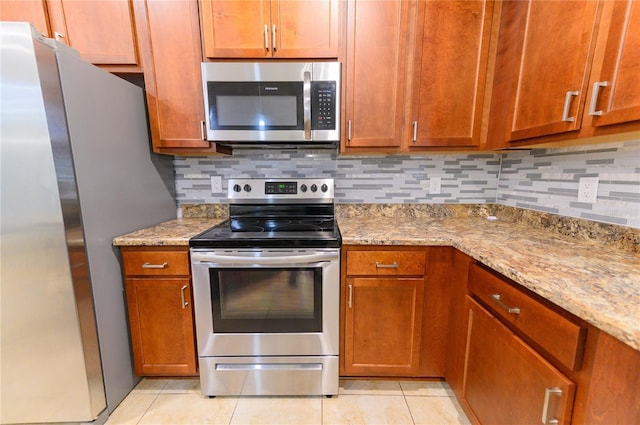 kitchen featuring light tile patterned flooring, decorative backsplash, stainless steel appliances, and light stone counters