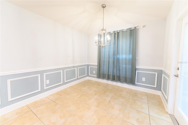 empty room featuring tile patterned floors, a wainscoted wall, an inviting chandelier, and a decorative wall