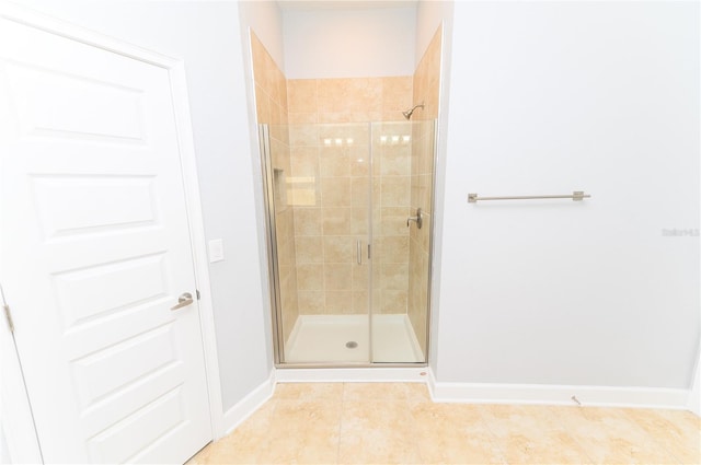 bathroom featuring tile patterned floors, a stall shower, and baseboards