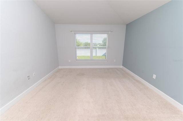 spare room featuring baseboards and light carpet