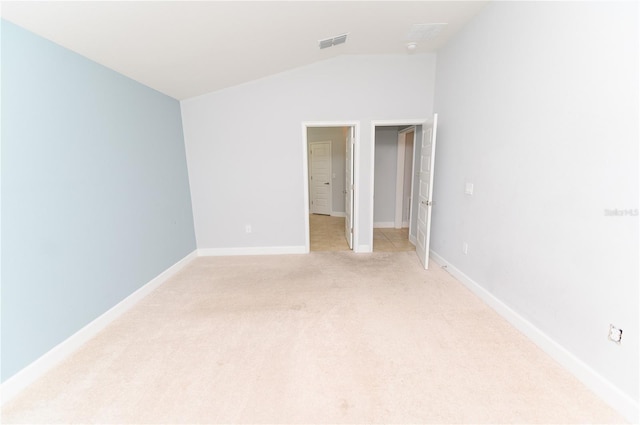 unfurnished bedroom featuring visible vents, light colored carpet, baseboards, and vaulted ceiling