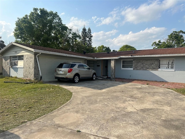 ranch-style home featuring cooling unit, an attached garage, concrete block siding, and driveway