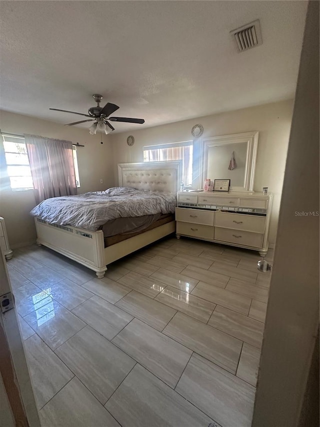 unfurnished bedroom featuring a ceiling fan, visible vents, and a textured ceiling