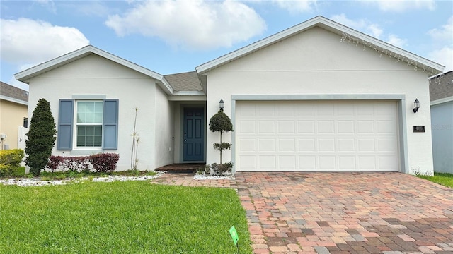 ranch-style house featuring stucco siding, decorative driveway, roof with shingles, a front yard, and an attached garage