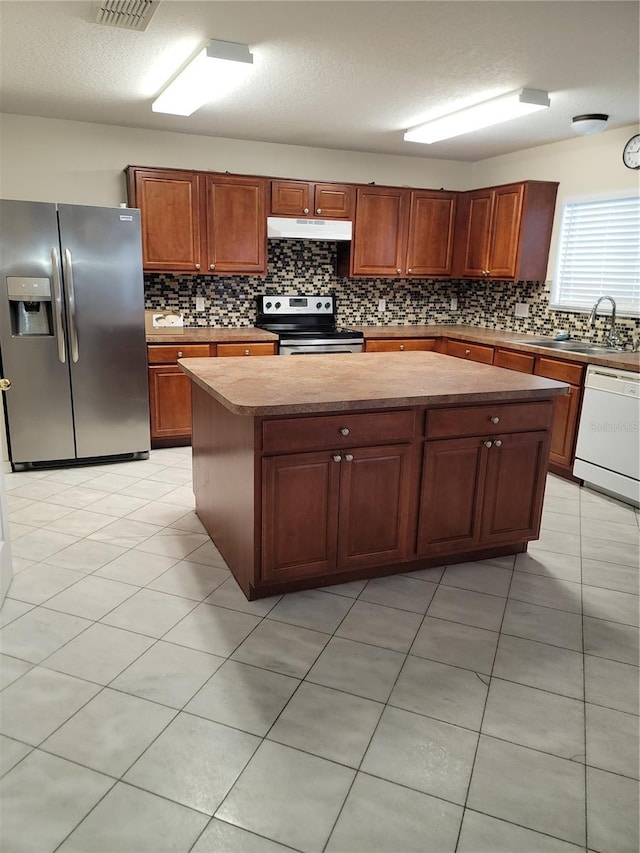 kitchen with a sink, stainless steel appliances, under cabinet range hood, tasteful backsplash, and a center island