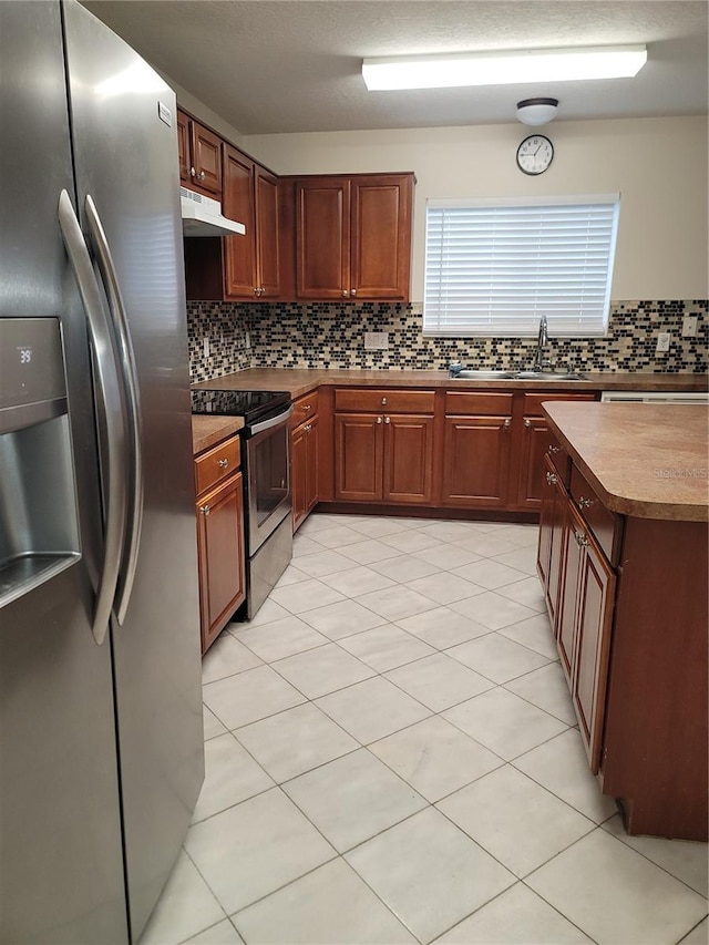 kitchen featuring under cabinet range hood, tasteful backsplash, appliances with stainless steel finishes, and a sink