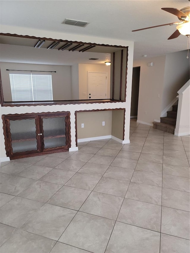 interior space featuring light tile patterned floors, visible vents, baseboards, and ceiling fan