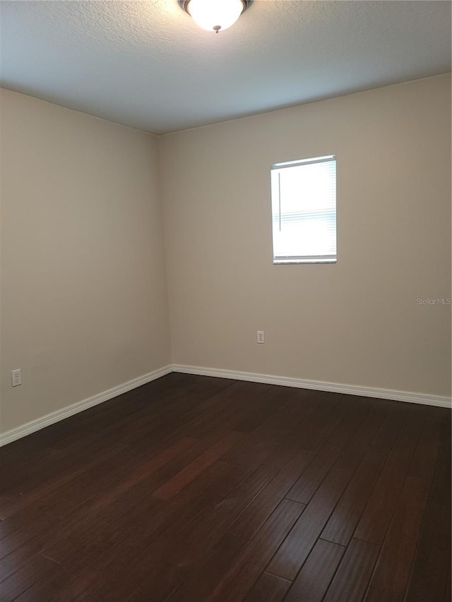 unfurnished room with dark wood-style floors, baseboards, and a textured ceiling