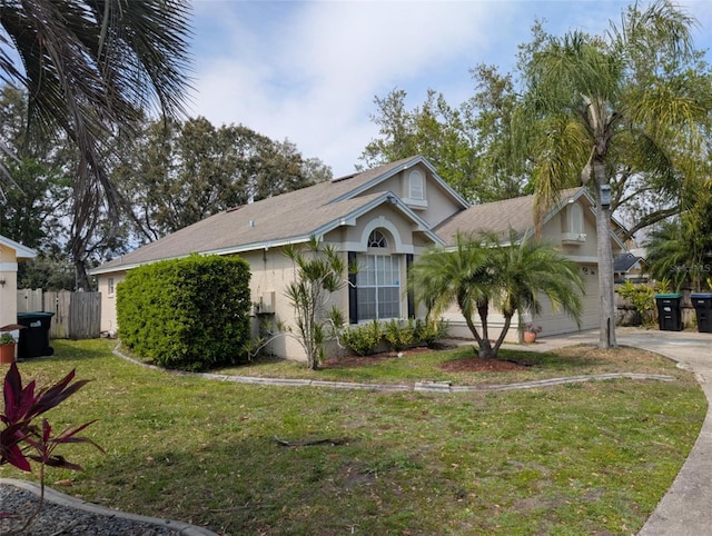 view of front of home with a front yard, fence, driveway, an attached garage, and stucco siding