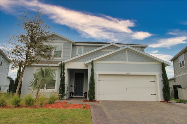 craftsman house with decorative driveway, an attached garage, and stucco siding