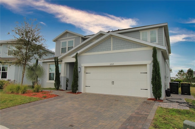 craftsman-style house with decorative driveway, an attached garage, and stucco siding