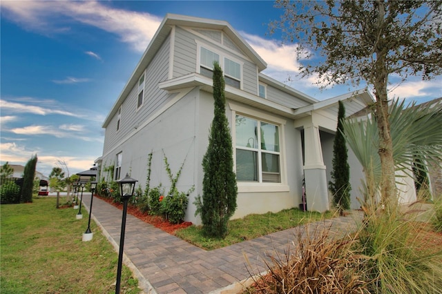 view of side of home with a yard and stucco siding