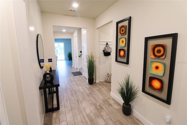 hall with wood finish floors, visible vents, and baseboards