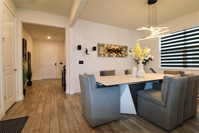 dining space with beam ceiling, baseboards, and wood finished floors