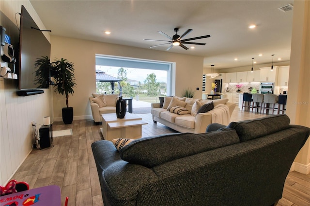 living area with baseboards, visible vents, recessed lighting, ceiling fan, and light wood-type flooring