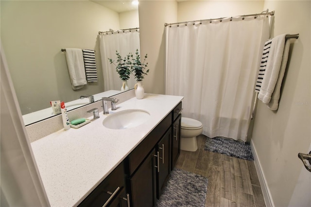 full bath with toilet, wood finished floors, a shower with shower curtain, baseboards, and vanity