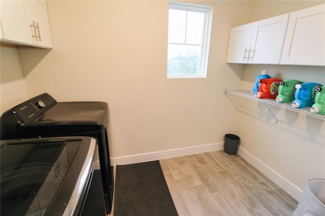 laundry area featuring cabinet space, light wood-style flooring, separate washer and dryer, and baseboards