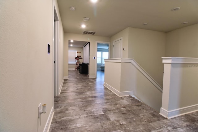 hall with visible vents, an upstairs landing, baseboards, and wood finished floors