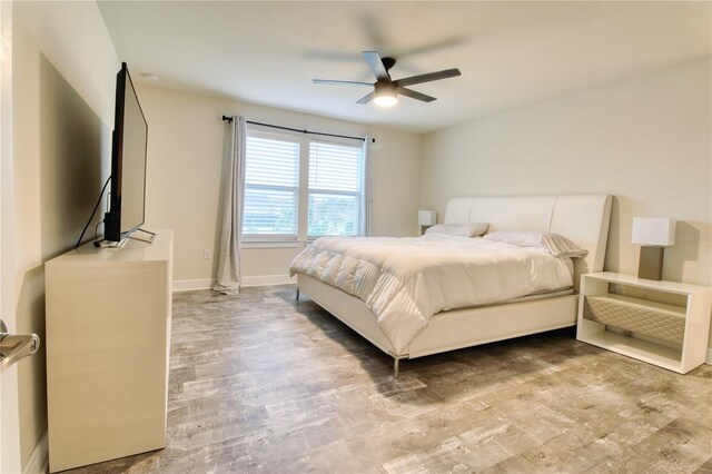 bedroom featuring ceiling fan, baseboards, and wood finished floors