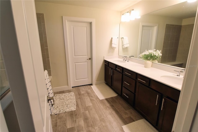 full bathroom with double vanity, wood finished floors, baseboards, and a sink