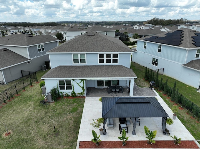 back of house featuring a patio, a fenced backyard, a shingled roof, a lawn, and a residential view