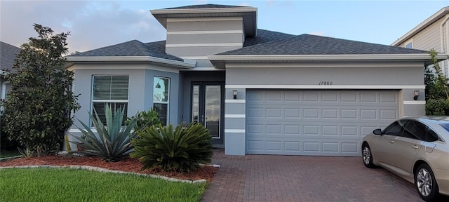 view of front of home featuring stucco siding, a shingled roof, decorative driveway, and a garage