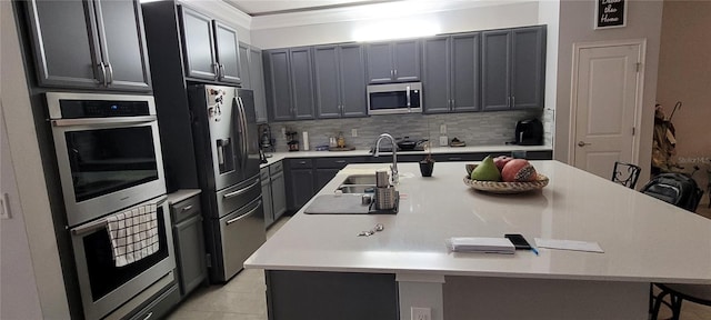 kitchen with a kitchen bar, decorative backsplash, a large island with sink, stainless steel appliances, and a sink