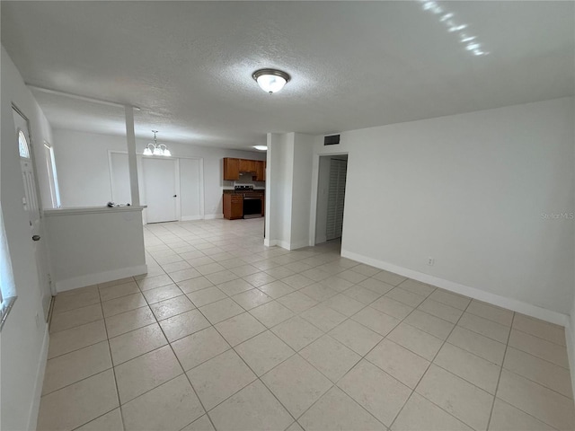 empty room featuring visible vents, baseboards, light tile patterned flooring, a notable chandelier, and a textured ceiling