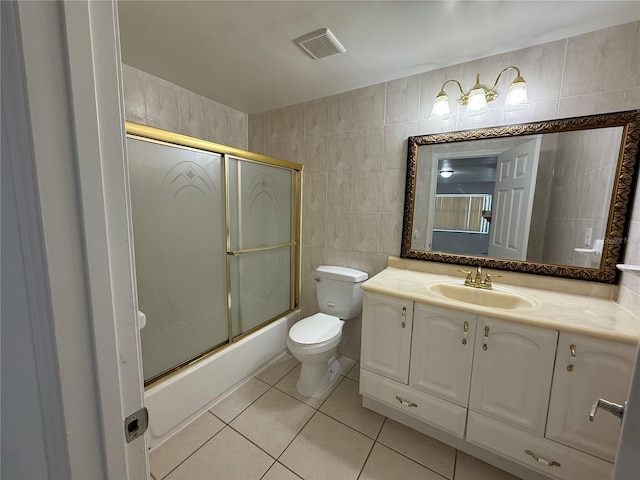 full bath featuring tile patterned flooring, visible vents, toilet, enclosed tub / shower combo, and tile walls