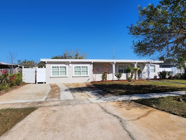 ranch-style house with a gate, stucco siding, a front lawn, and fence