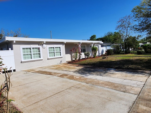 ranch-style home with concrete driveway, fence, and stucco siding