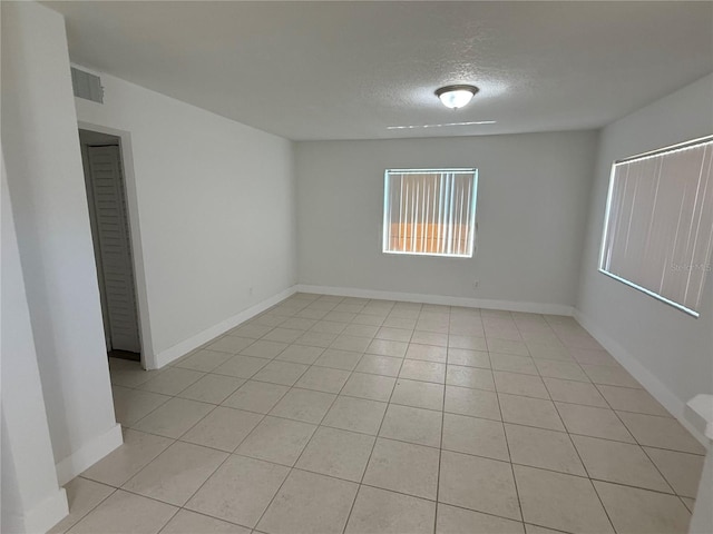 spare room featuring visible vents, a textured ceiling, and baseboards