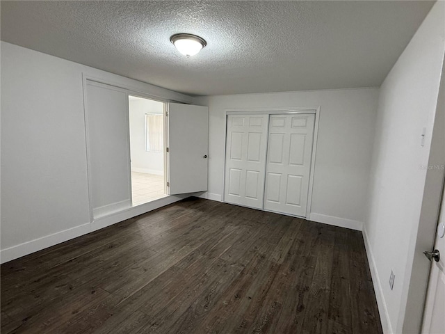 unfurnished bedroom with a closet, baseboards, a textured ceiling, and dark wood-style flooring