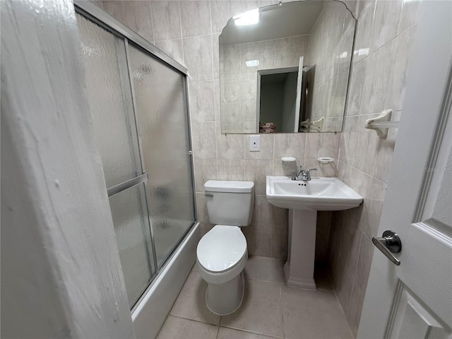 full bath with enclosed tub / shower combo, a sink, tile patterned floors, toilet, and tile walls