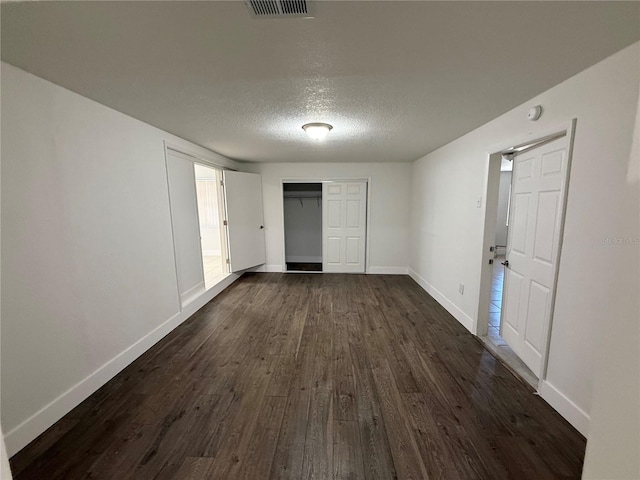 unfurnished room featuring dark wood finished floors, visible vents, a textured ceiling, and baseboards