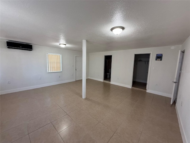 basement with baseboards, a wall mounted air conditioner, and a textured ceiling