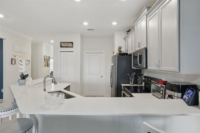 kitchen with visible vents, a sink, light countertops, appliances with stainless steel finishes, and a kitchen breakfast bar