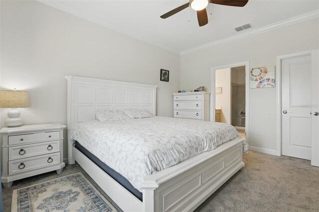 carpeted bedroom with visible vents, crown molding, ceiling fan, baseboards, and ensuite bath